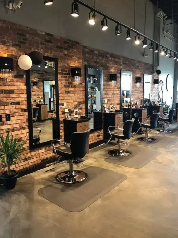 Salão de barbearia com parede de tijolinho e espelhos